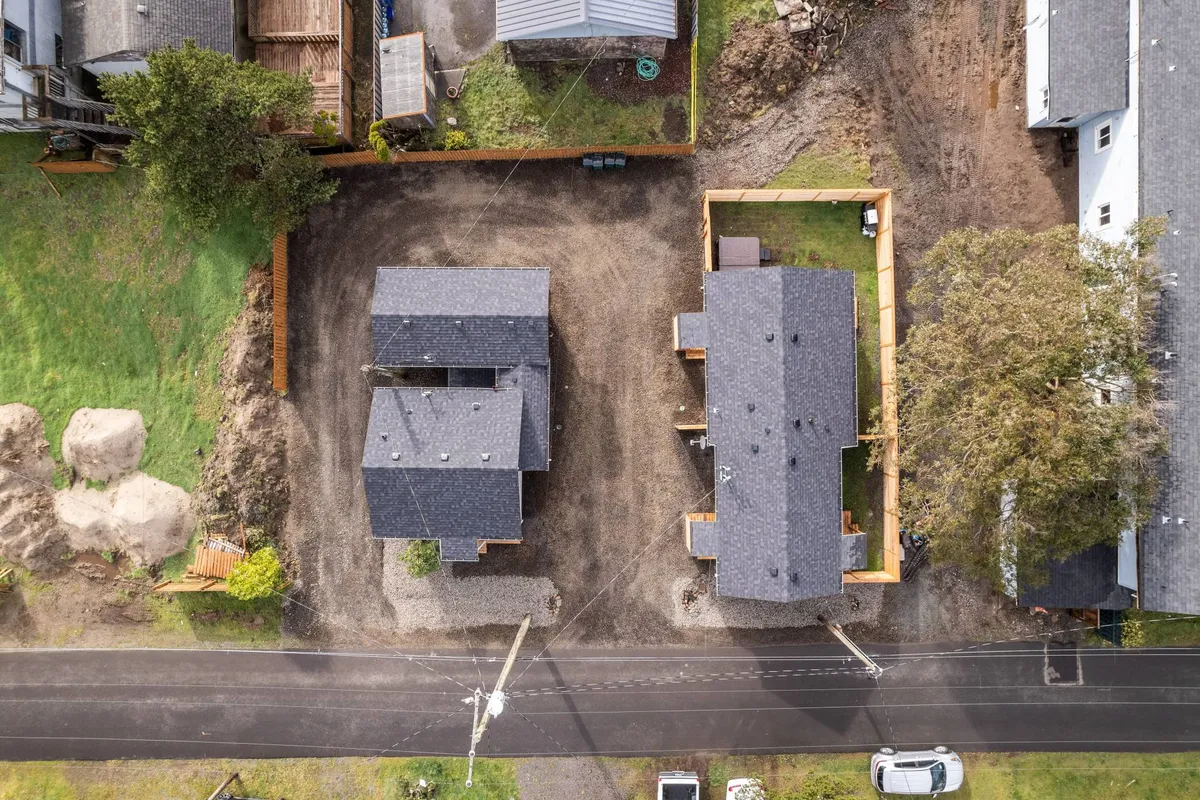 The exterior view features two cottages surrounded by greenery and a gravel area, creating a peaceful communal space ideal for gatherings or relaxing moments outdoors.
