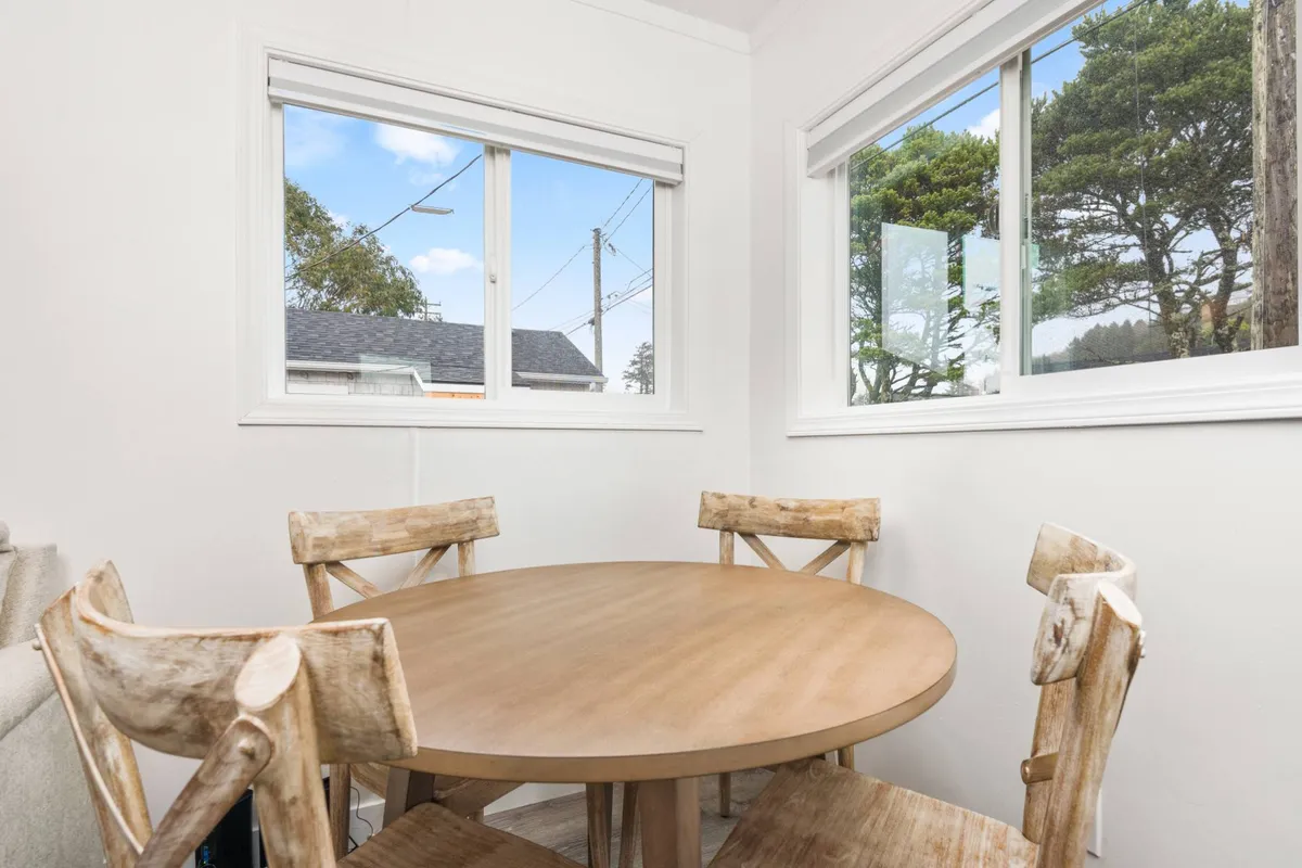 A cozy dining nook with a round wooden table and matching chairs, set beside large windows that let in an abundance of natural light. The warm, inviting setting is ideal for casual breakfasts or intimate dinners.